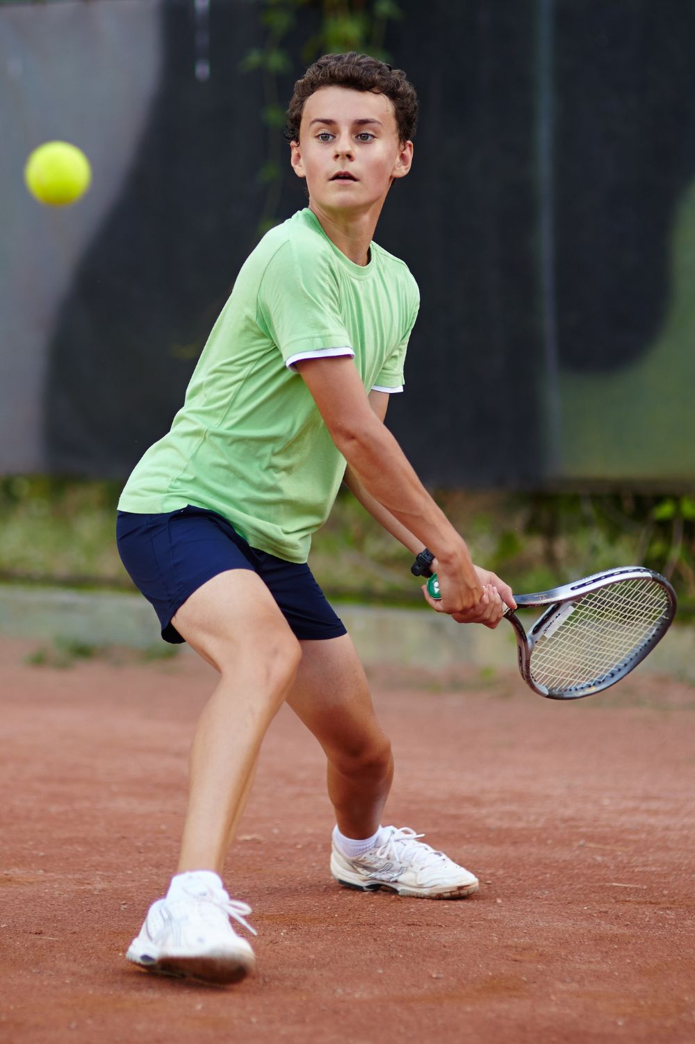 Junior player hitting a backhand on court